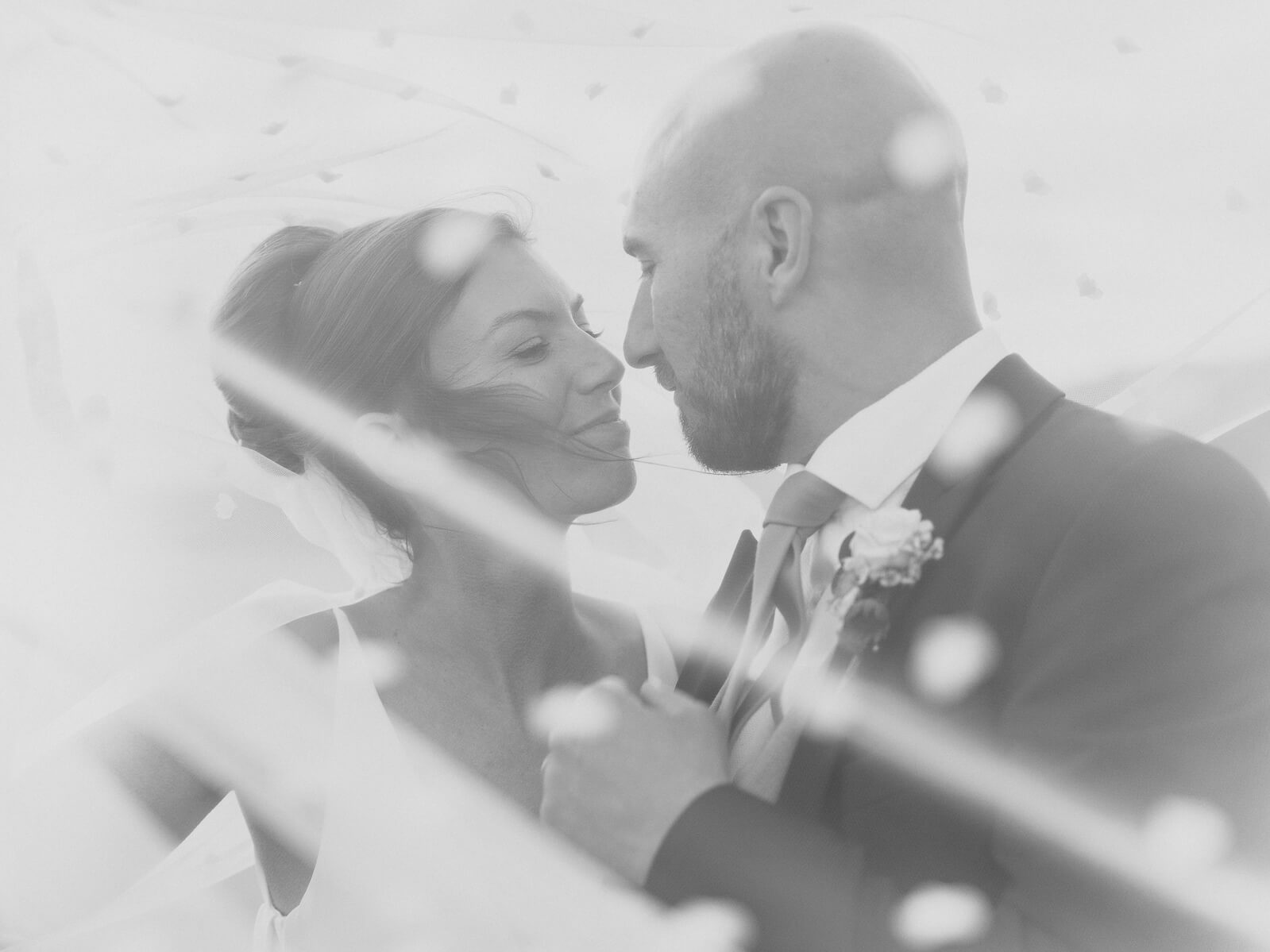 Bride and groom portrait through veil in black and white.