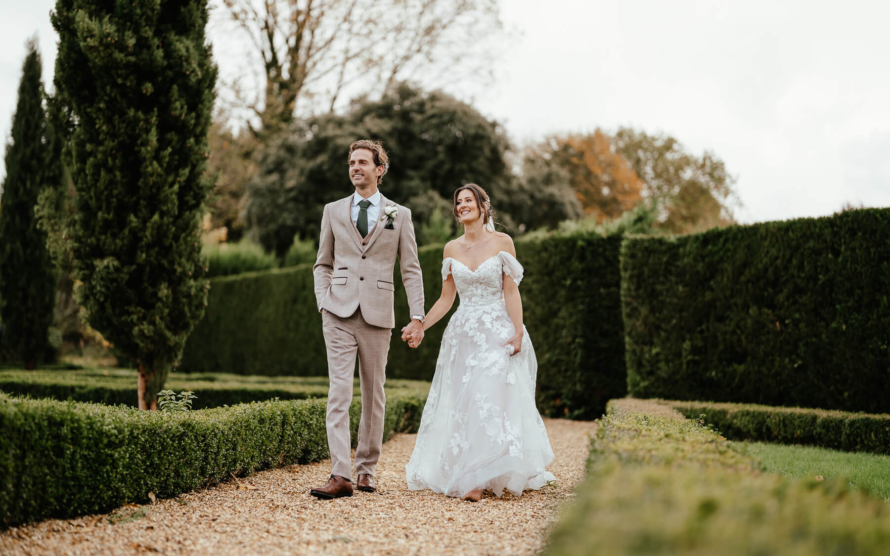 Bride and groom walking through walled garden.
